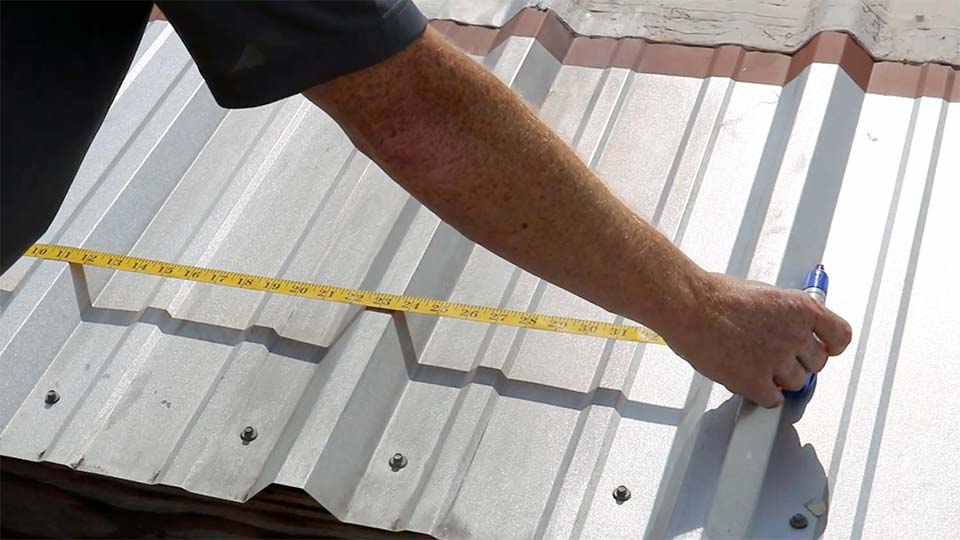 a man is measuring metal roofing